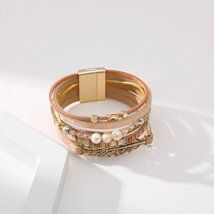 Détail d'un bracelet bohème multicouche avec breloque plume dorée et fermoir magnétique