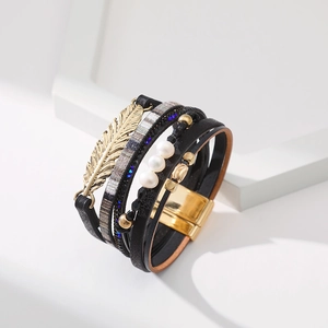 Détail du bracelet multicouche en cuir bohème avec breloque feuille dorée et fermoir magnétique