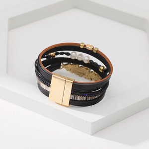 Détail d'un bracelet bohème multicouche avec pendentif plume dorée et fermoir magnétique