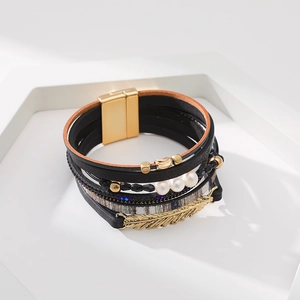 Détail du bracelet multicouche bohème avec fermoir magnétique, perles et plume dorée