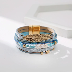 Détail du bracelet multicouche bohème avec pendentif plume dorée et fermoir magnétique