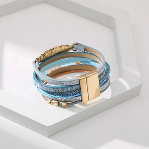 Détail du bracelet bohème multicouche en cuir avec strass turquoise et breloque en plume d'or