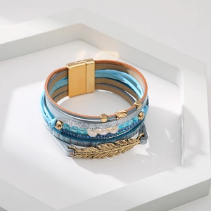 Détail d'un bracelet de style bohème en cuir multicouche avec plume et perles