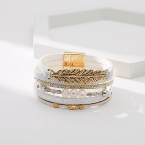 Détail du bracelet multicouche en cuir bohème avec plume dorée et fermoir magnétique