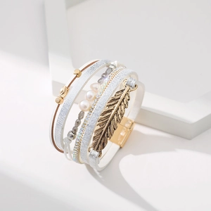 Détail macro du bracelet multicouche en cuir bohème avec perles et plume dorée