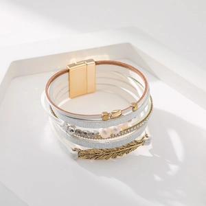 Détail macro du bracelet bohème multicouche en cuir avec perles et breloque feuille