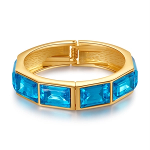 Dettaglio di bracciale dorato con pietre rettangolari blu e chiusura a molla metallica