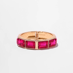 Dettaglio del bracciale rigido dorato con pietre preziose rettangolari magenta