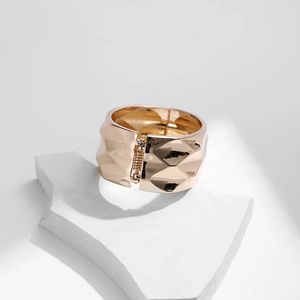 Detailed close-up of wide golden metal cuff with 3D diamond pattern and spring hinge