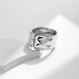 Close-up of wide silver metal bangle with geometric facets and hinged closure