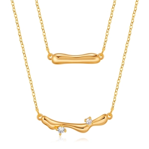 Detail of layered gold necklaces featuring minimalist heart and wave zircon pendants