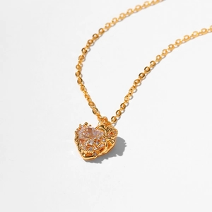 Macro shot of gold-plated heart necklace featuring a large faceted clear zircon stone