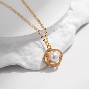 Dettaglio di una collana in oro e zirconi con pendente a doppio anello e perla da 8mm