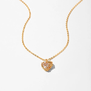 Close-up of golden heart pendant necklace featuring a large clear zircon and fine chain