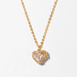 Macro shot of gold heart pendant necklace featuring a sparkling zircon center stone