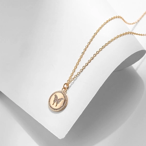 Dettaglio macro di una collana a farfalla dorata con zirconi su base bianca
