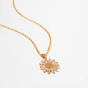Close-up of golden sunflower pendant necklace featuring sparkling marquise petals