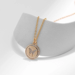 Dettaglio pendente a farfalla dorato con zirconi micro-pave su catena a maglie