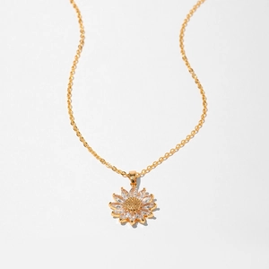 Detail shot of a delicate gold necklace with a sunflower pendant and zircon petals