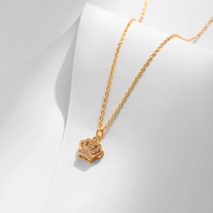 Dettaglio ravvicinato di una collana con ciondolo a corona dorata e zirconi bianchi lucenti