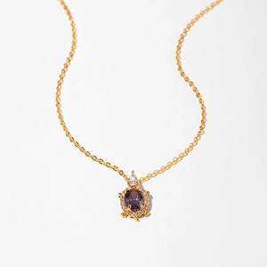 Detail of gold turtle necklace featuring purple oval gemstone and white zircon accents