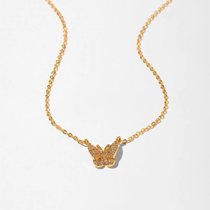 Detail shot of a delicate gold butterfly necklace pendant with pavé set white zircon stones