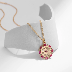 Dettaglio della collana con medaglione malocchio dorato con rubini e cristalli
