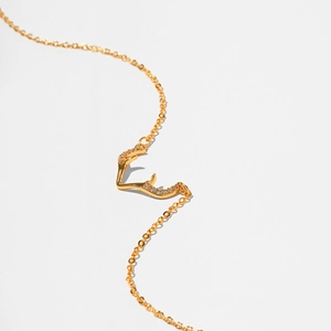 Macro shot of gold reindeer antler necklace with sparkling zircon pavé on white background