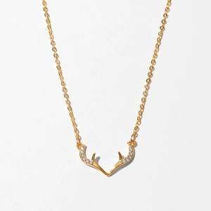 Detailed close-up of a gold antler pendant necklace featuring sparkling white zircon stones