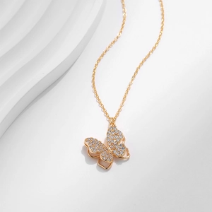 Dettaglio di una collana a farfalla placcata in oro con pavé di zirconi su sfondo bianco
