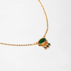 Detail of gold necklace with marquise green stone and colorful swaying gemstone tassels