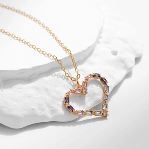 Dettaglio del ciondolo a cuore cavo con zirconi viola e rosa su una catena d'oro