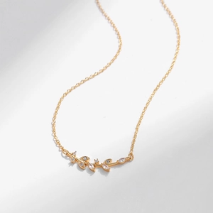 Dettaglio della collana in oro con foglie d'ulivo, pietre di zircone e catena a maglia