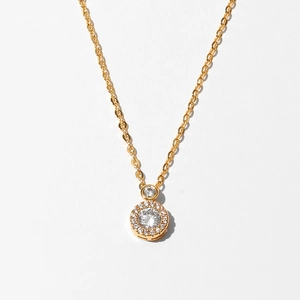 Detailed macro view of a gold pendant necklace with a circular halo and sparkling crystals