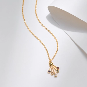 Dettaglio della collana con pendente a ventaglio e zirconi colorati su catena dorata