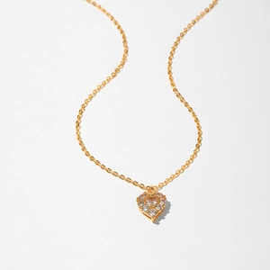 Detailed close-up of a golden heart necklace featuring sparkling zircon inlay and thin O-chain