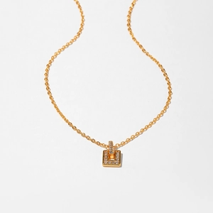 Detailed macro view of a gold-toned necklace featuring a rectangle zircon-set pendant