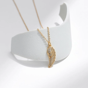 Dettaglio macro di una collana con ciondolo ad ala d'angelo placcata in oro e zirconi