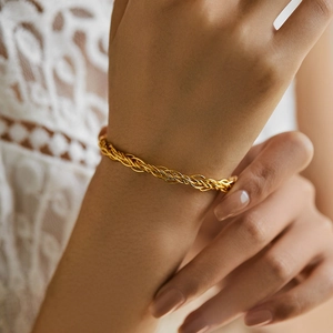 Détail d'un bracelet jonc tressé plaqué or 18 carats sur le poignet d'une femme