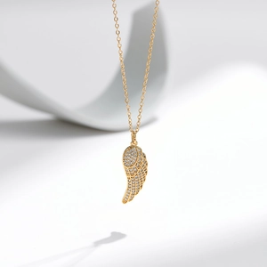 Dettaglio della collana con pendente ala d'angelo dorata e pietre in zircone bianco