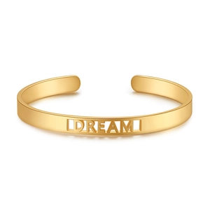 Detailansicht eines goldenen Armreifs mit filigranem DREAM-Schriftzug in Cut-out-Design