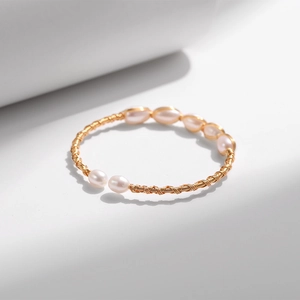 Makrodetail der handgewickelten Goldmetalltextur mit glänzenden rosa Süßwasserperlen