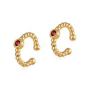 Détail macro de boucles d'oreilles dorées perlées avec pierres en zircon rouge
