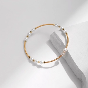 Detaillierte Makroansicht des Armbands mit Süßwasserperlen und goldener Metallspirale