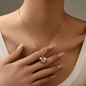 Golden heart pendant necklace with pink gemstone and crystals worn by a model
