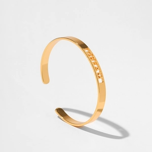 Vista dettagliata del bracciale rigido dorato aperto con incisione della scritta DREAM