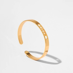 Dettaglio del bracciale rigido dorato con scritta LOVE traforata e finitura metallica