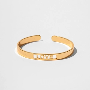 Dettaglio del bracciale aperto dorato con finitura lucida e design intagliato LOVE