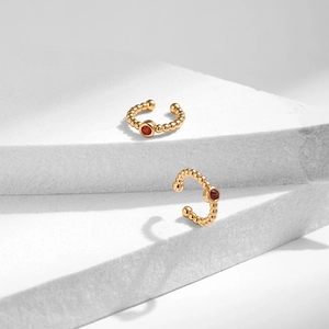 Détail de bagues d'oreilles en laiton plaqué or 18K avec zircon rouge et texture perlée