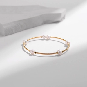 Detail eines vergoldeten Armbands mit sechs Perlen und besonderer Federstruktur